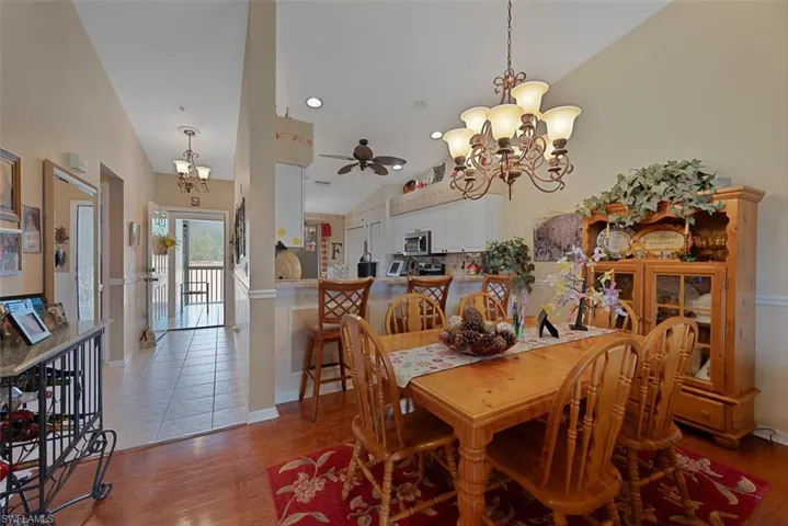 Dining room featuring lofted ceiling, a chandelier, a ceiling fan, and wood finished floors