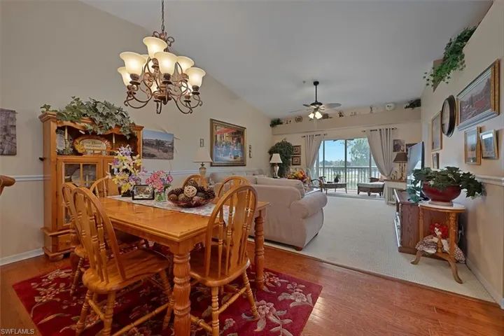 Dining room featuring ceiling fan, wood finished floors, a chandelier, and lofted ceiling