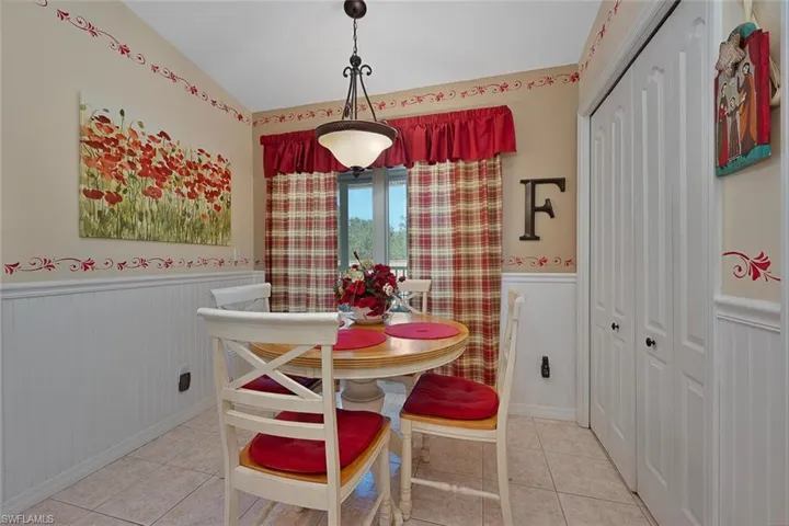 Dining room featuring a wainscoted wall, tile patterned flooring, and vaulted ceiling