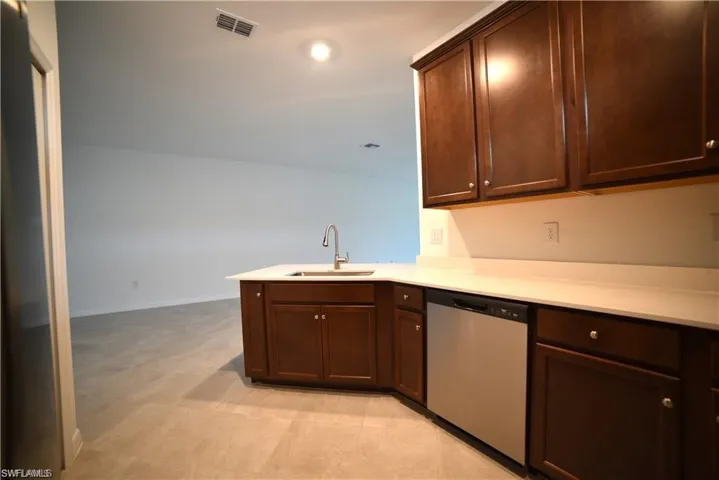 Kitchen featuring stainless steel dishwasher, dark brown cabinets, a peninsula, and recessed lighting