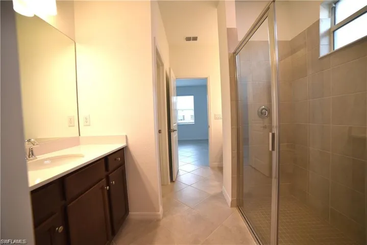 Bathroom featuring a shower stall, vanity, and light tile patterned floors