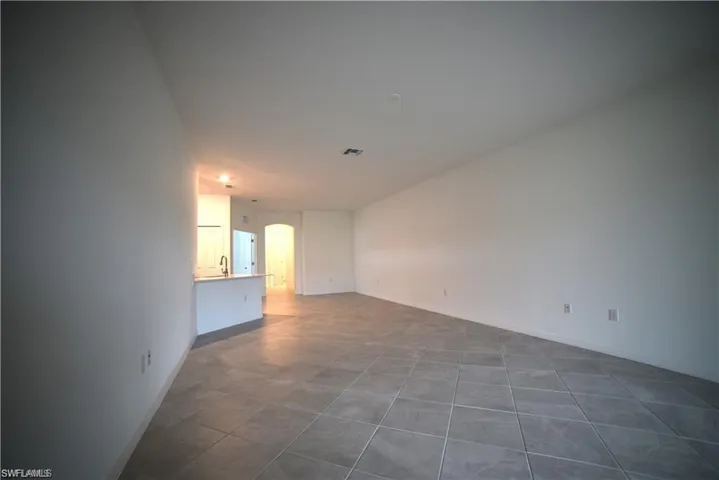 Unfurnished living room with arched walkways and dark tile patterned floors