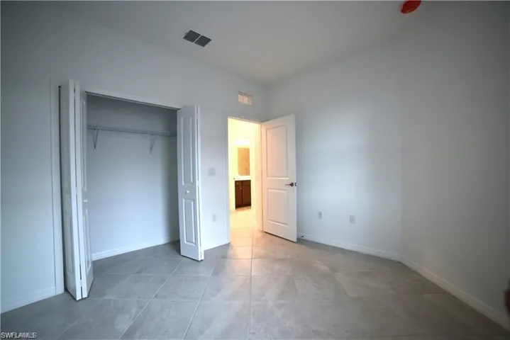 Unfurnished bedroom with a closet and light tile patterned flooring