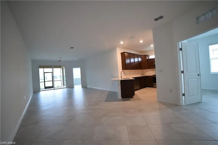 Kitchen featuring open floor plan, dark brown cabinets, recessed lighting, light tile patterned floors, and a peninsula