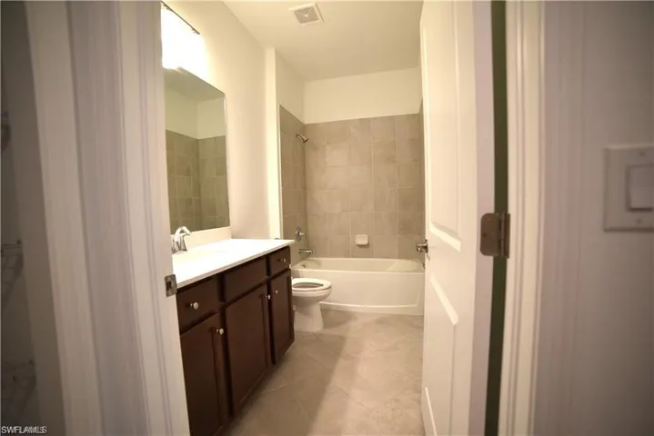 Bathroom featuring vanity, shower / bathtub combination, and light tile patterned floors