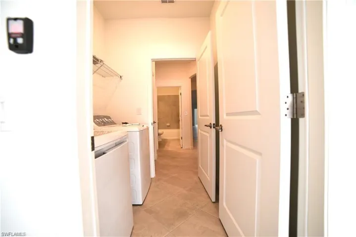 Laundry area with washing machine and dryer and light tile patterned floors