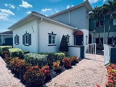 Stucco exterior with decorative shutters, clay tile roof, and a red awning