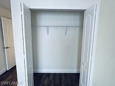 White bi-fold closet doors with panel detailing, wire shelving, and wood-finish flooring
