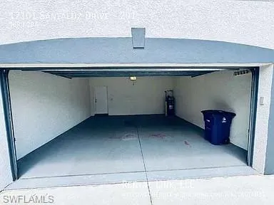 Spacious garage with an overhead door, smooth concrete flooring, and an interior access door