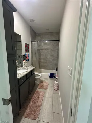 Full bathroom with toilet, vanity, and shower / bath combination with curtain