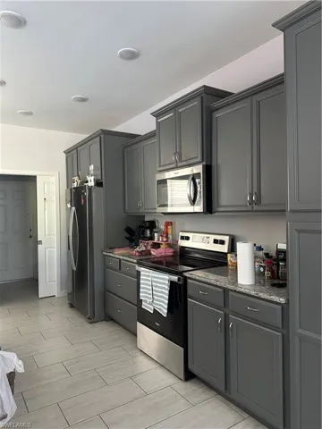 Kitchen featuring range, refrigerator, dark stone counters, and gray cabinets