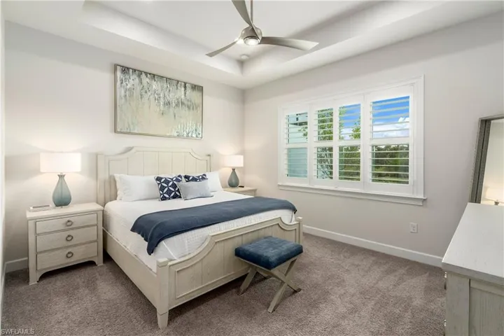 Bedroom with carpet flooring, a raised ceiling, and ceiling fan