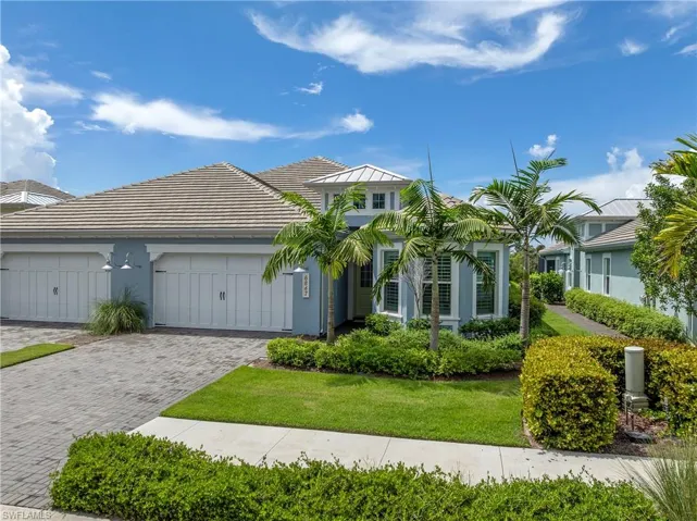 View of front facade featuring stucco siding, decorative driveway, a garage, and a front lawn