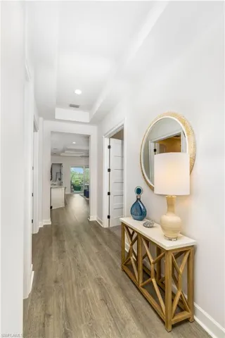 Hallway with wood finished floors and a tray ceiling