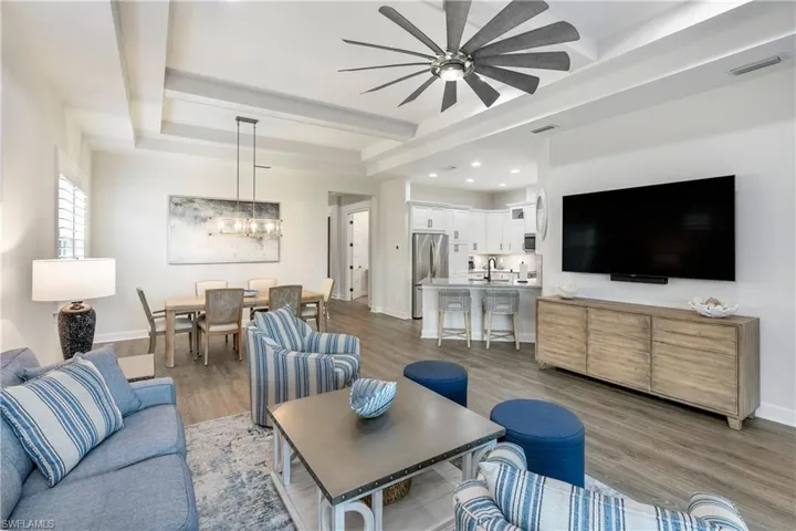 Living room with wood finished floors, a chandelier, a raised ceiling, and recessed lighting