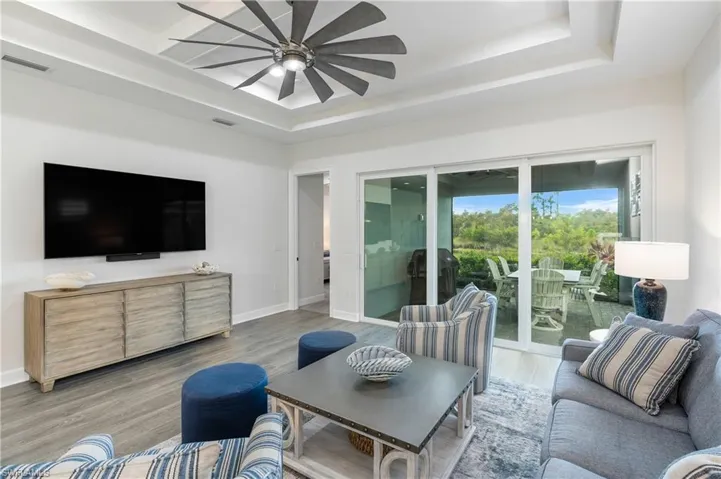 Living area featuring wood finished floors, a tray ceiling, and a ceiling fan