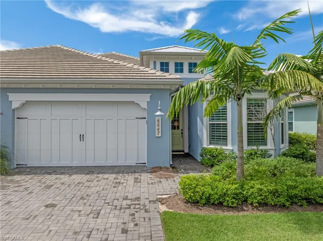 View of front facade with a tiled roof, decorative driveway, stucco siding, and a garage
