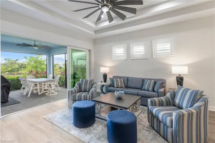 Living room featuring ceiling fan, wood finished floors, healthy amount of natural light, and a raised ceiling