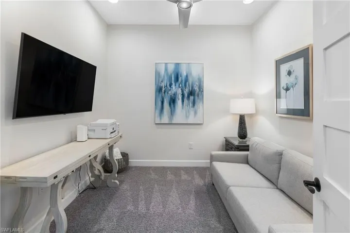 Living area with dark carpet and recessed lighting