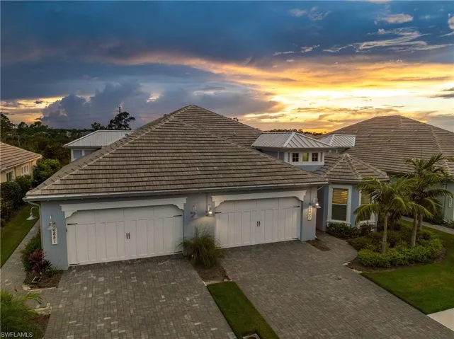 View of front of property with stucco siding, a tiled roof, decorative driveway, and an attached garage