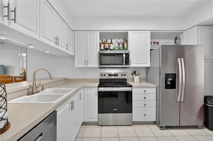 Kitchen with stainless steel appliances, light countertops, and white cabinetry