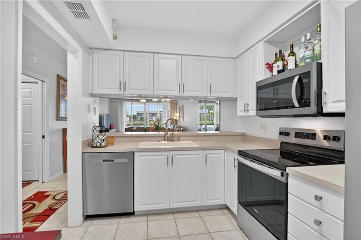 Kitchen with stainless steel appliances, white cabinetry, light countertops, and light tile patterned flooring