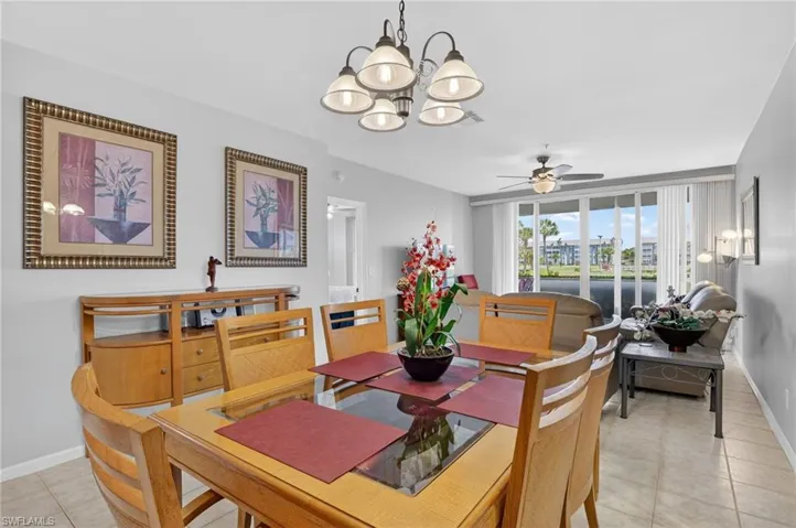 Dining area featuring a chandelier, light tile patterned floors, and a ceiling fan