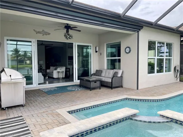 View of pool with a patio, ceiling fan, screen enclosure, and an outdoor living space