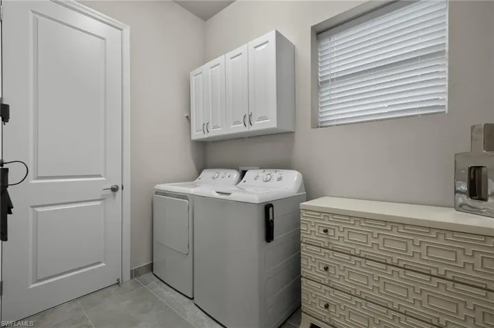 Gently used Laundry area with cabinets, washer and dryer, and porcelain tile patterned floors