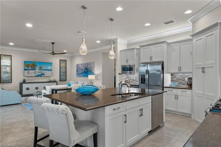 Kitchen with appliances with stainless steel finishes, sink, ceiling fan, decorative backsplash, and a extra large center island with sink