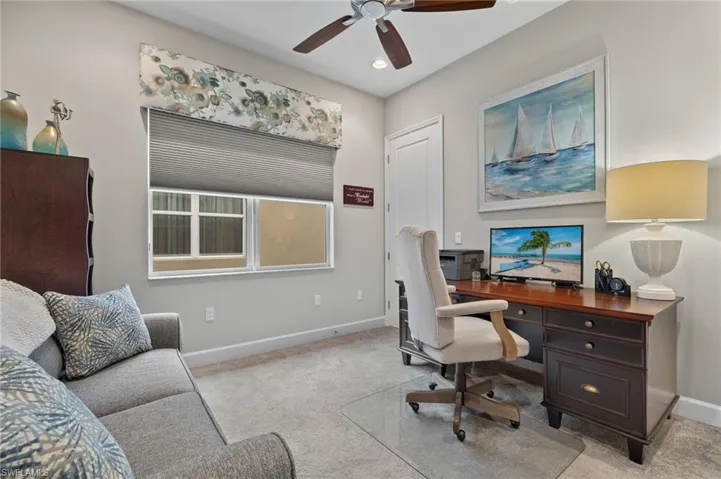 Office area featuring light colored carpet and ceiling fan, deep closet