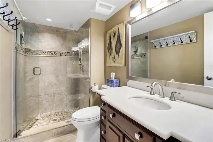 Bathroom featuring tile floors, an enclosed shower, oversized vanity, and toilet
