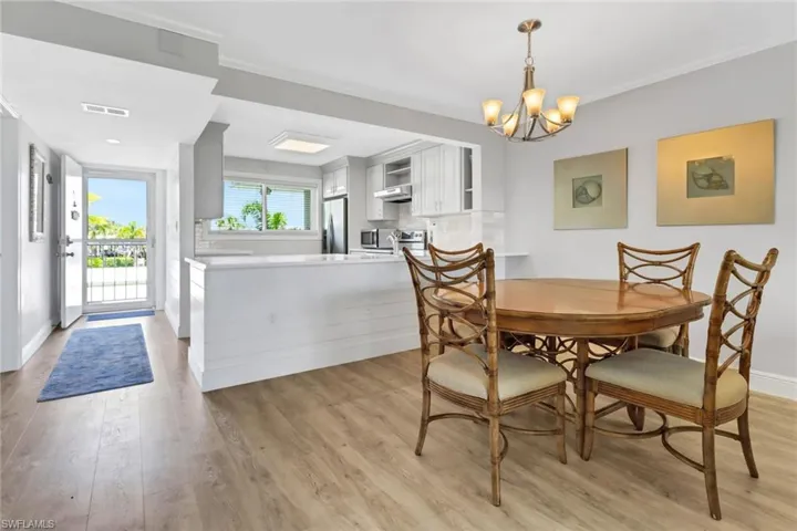 Dining space featuring crown molding, light wood-type flooring, and an inviting chandelier