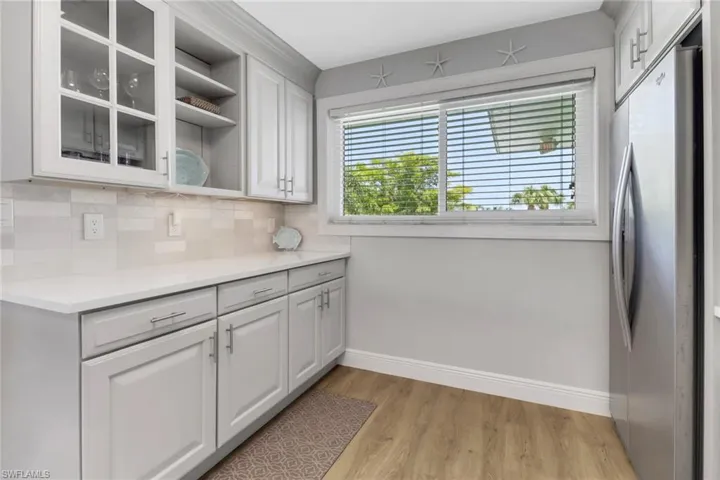 Kitchen featuring white cabinets, stainless steel fridge, light hardwood / wood-style floors, and tasteful backsplash