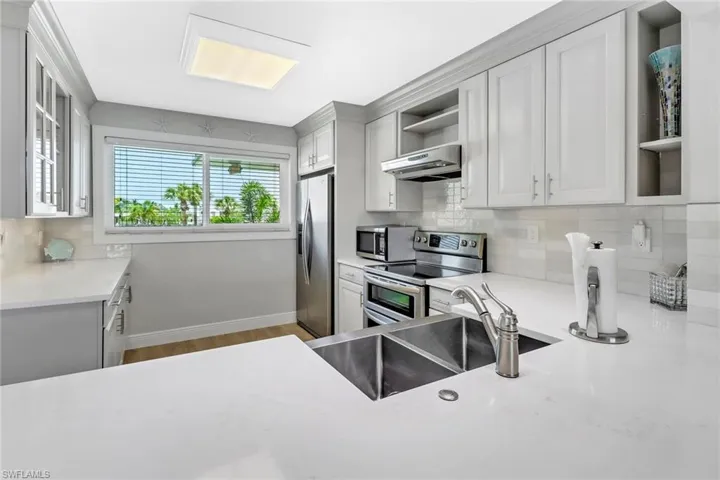 Kitchen featuring backsplash, appliances with stainless steel finishes, sink, and hardwood / wood-style flooring