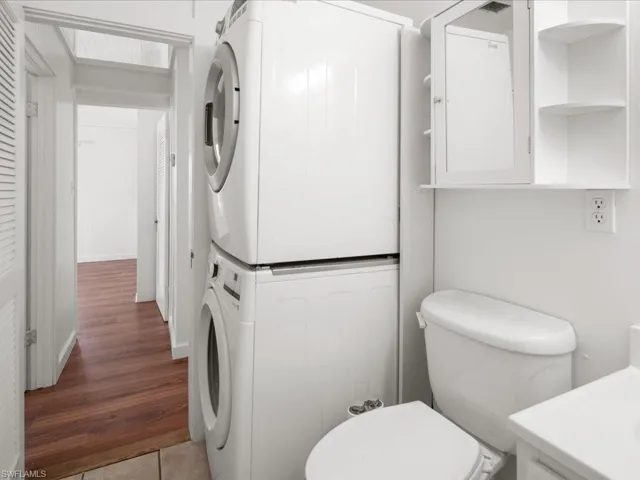 Laundry area with hardwood / wood-style floors and stacked washer and clothes dryer