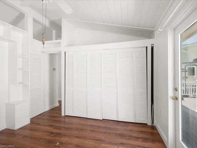 Unfurnished bedroom featuring ceiling fan, vaulted ceiling, and dark hardwood / wood-style flooring