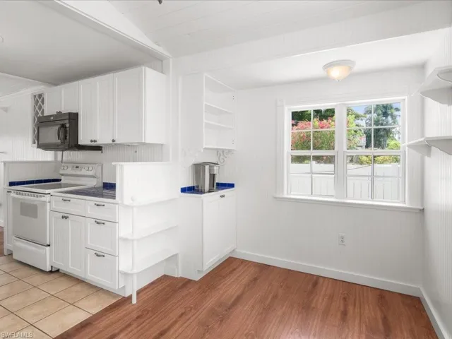 Kitchen featuring electric stove, white cabinets, backsplash, and light tile floors