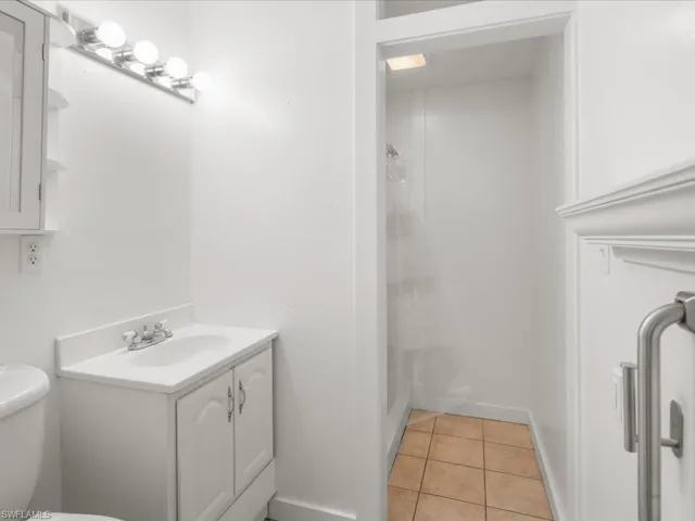 Bathroom with vanity with extensive cabinet space, toilet, and tile floors
