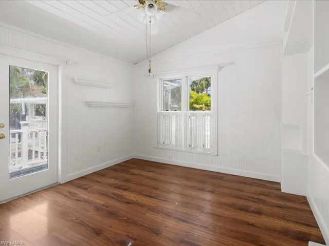 Spare room featuring dark hardwood / wood-style floors, ceiling fan, and lofted ceiling
