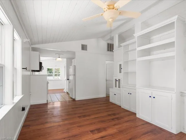 Unfurnished living room featuring dark wood-type flooring, ceiling fan, and vaulted ceiling