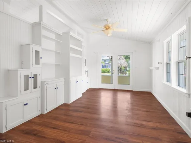 Unfurnished living room featuring crown molding, french doors, dark hardwood / wood-style flooring, built in features, and ceiling fan