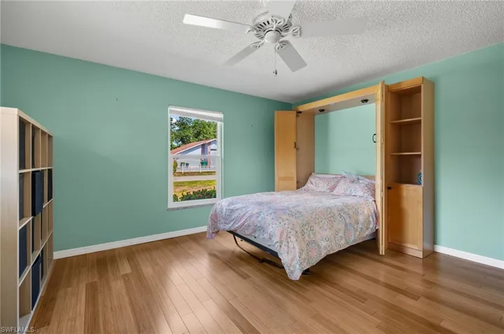 Bedroom featuring ceiling fan, a textured ceiling, and hardwood / wood-style flooring