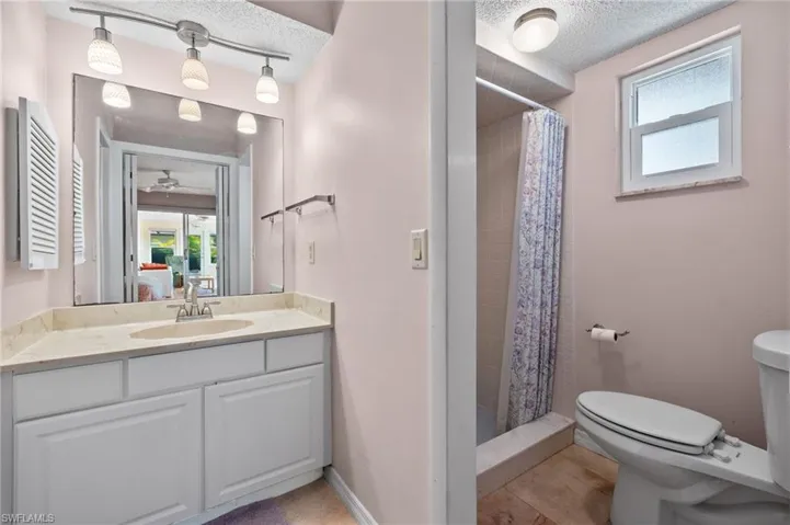 Bathroom featuring a textured ceiling, curtained shower, toilet, tile patterned floors, and vanity