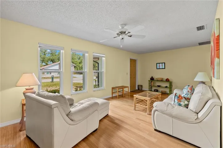 Living room with light hardwood / wood-style flooring, a textured ceiling, and ceiling fan
