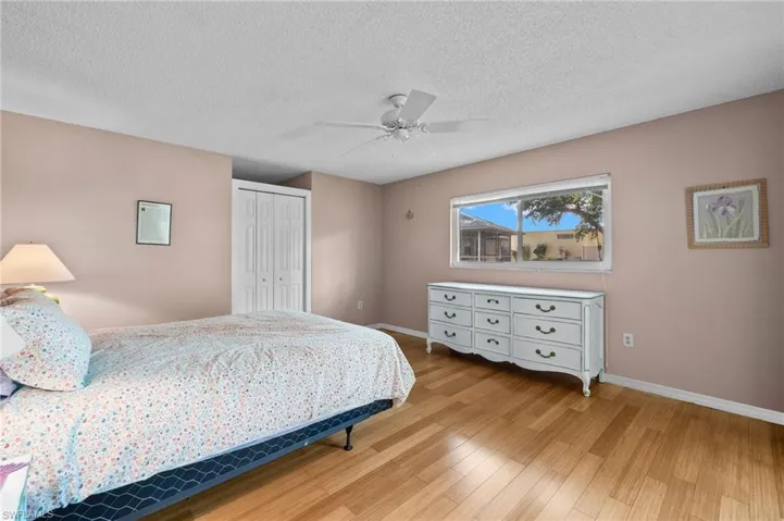 Bedroom featuring a textured ceiling, a closet, ceiling fan, and light hardwood / wood-style floors