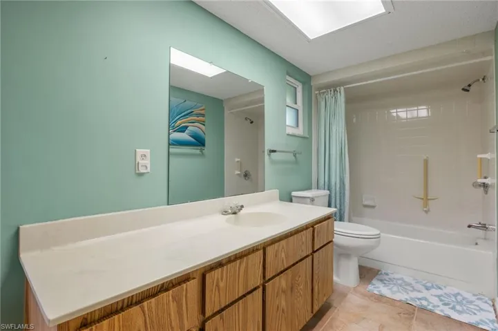 Full bathroom with shower / tub combo, vanity, toilet, and tile patterned flooring