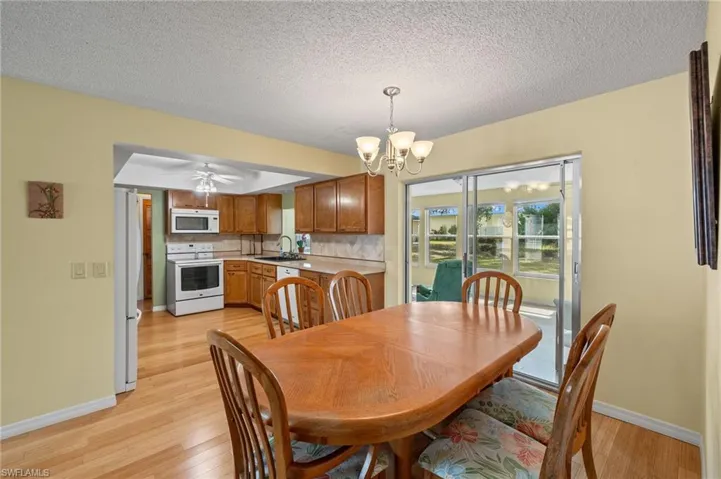 Dining area featuring light wood-type flooring, sink, a textured ceiling, and ceiling fan with notable chandelier