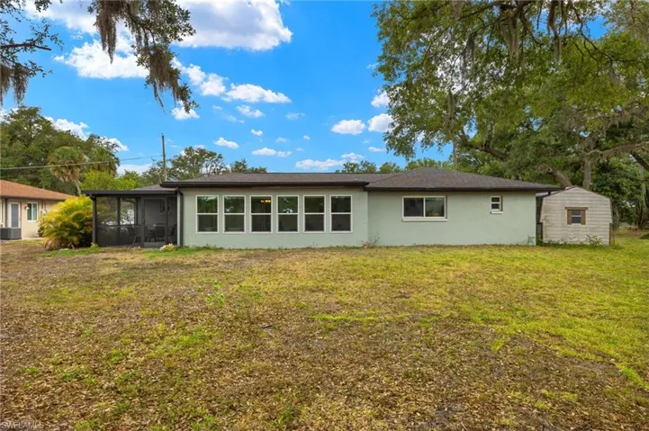Back of house with central AC, a lawn, and a sunroom