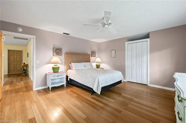 Bedroom featuring ceiling fan, light wood-type flooring, a textured ceiling, and a closet